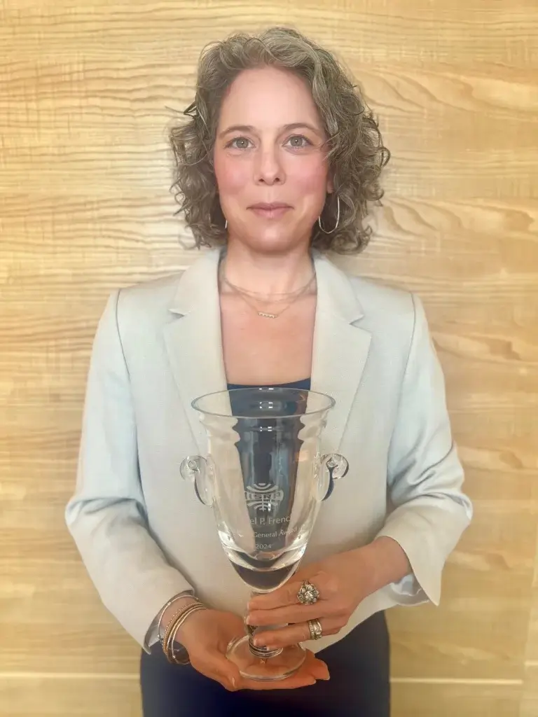 French Oil Machinery Co. CEO Tayte French Lutz holding a glass award for IISRP General Award for outstanding contributions. Daniel P. French was posthumously honored with the award.