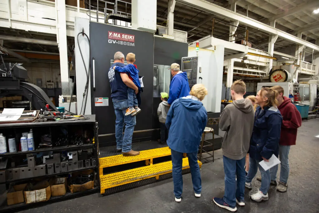 People viewing a CNC machin in French Oil's machining area.